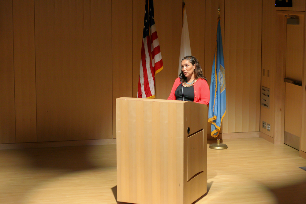 Jennifer De Leon stands behind a podium.